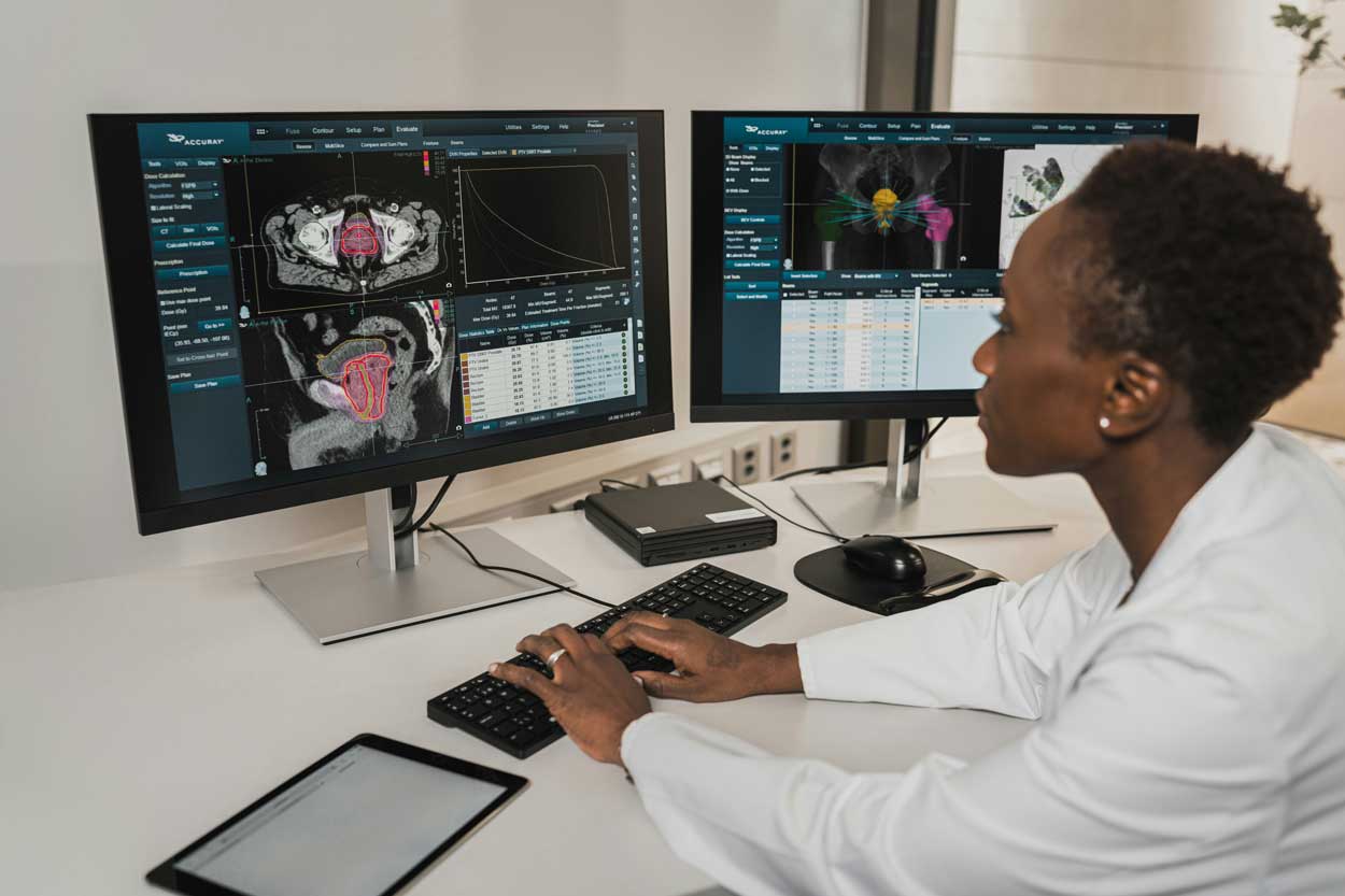 A woman in a white coat assesses scans on her computer screen.