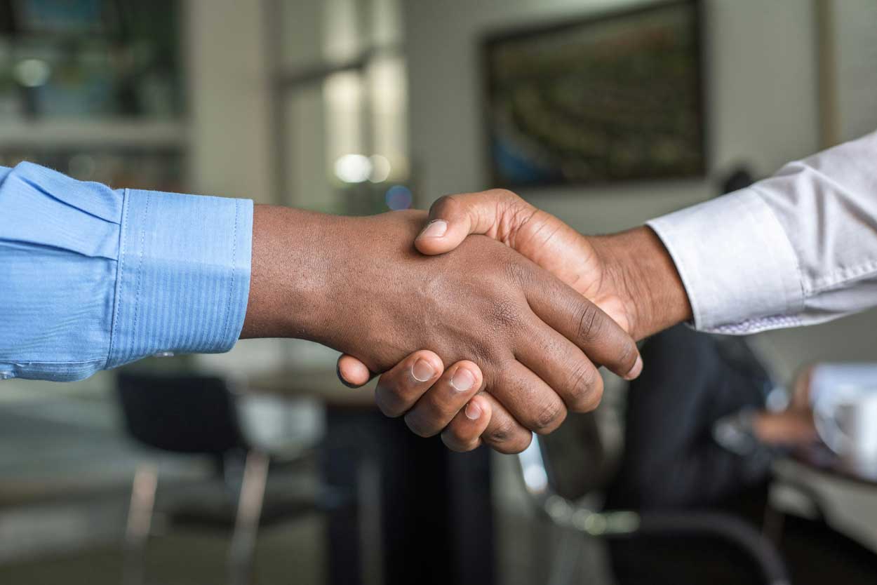 A closeup of two people in business casual shaking hands.