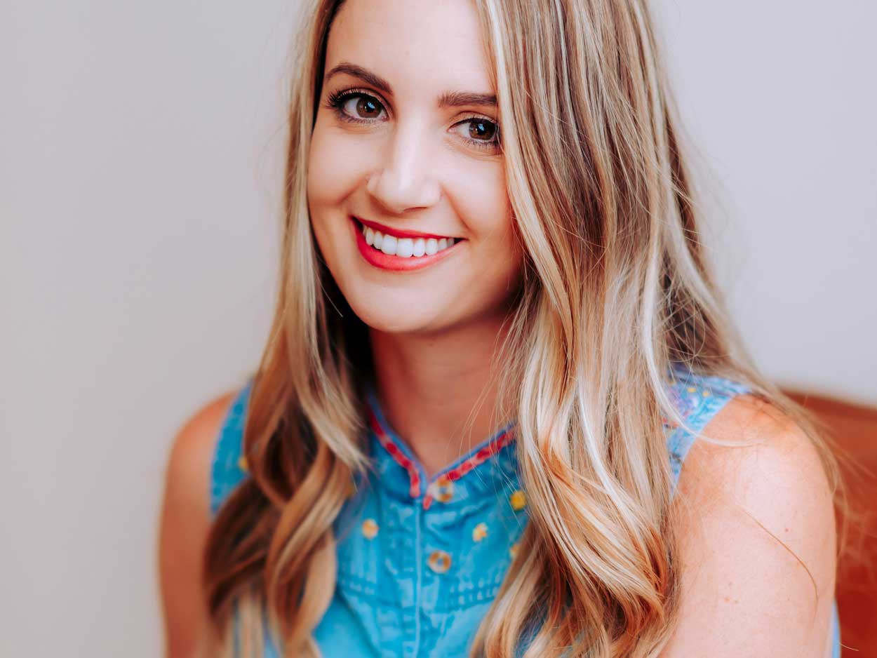 A young woman with straight blonde hair smiles at the camera.